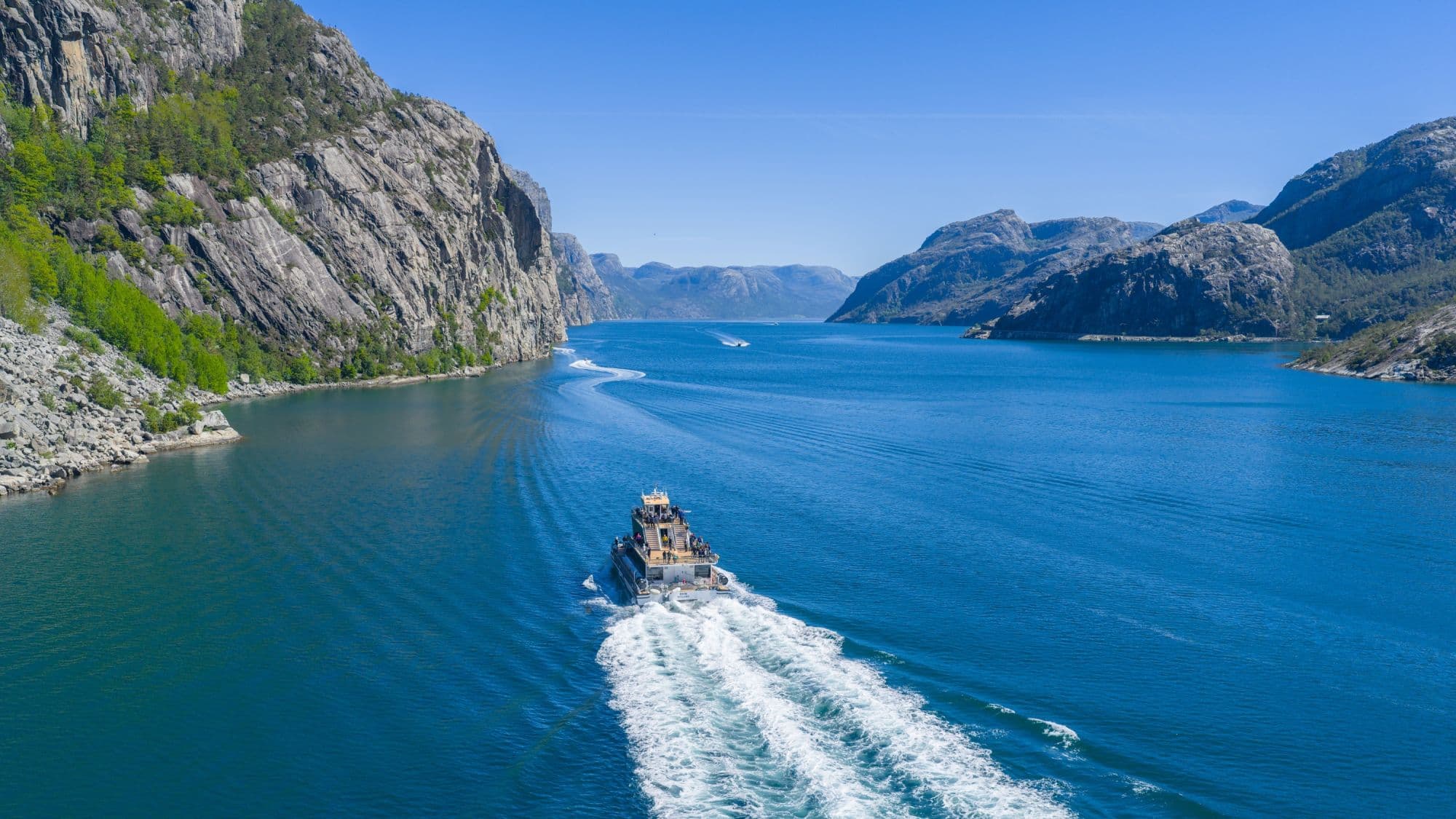 Sightseeing boat in the fjords, blue fjord and towering mountains