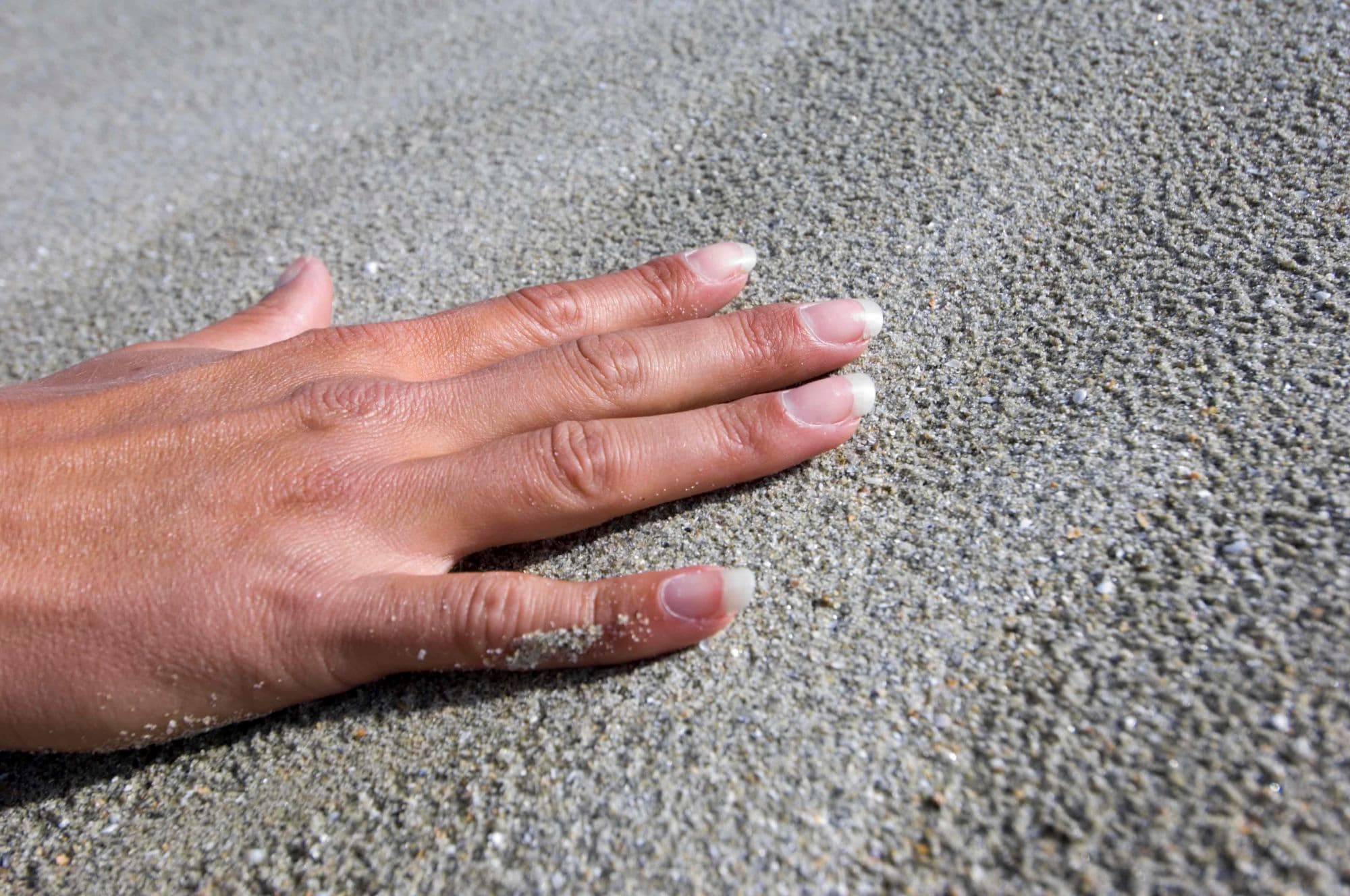 Hand touching sand on beach