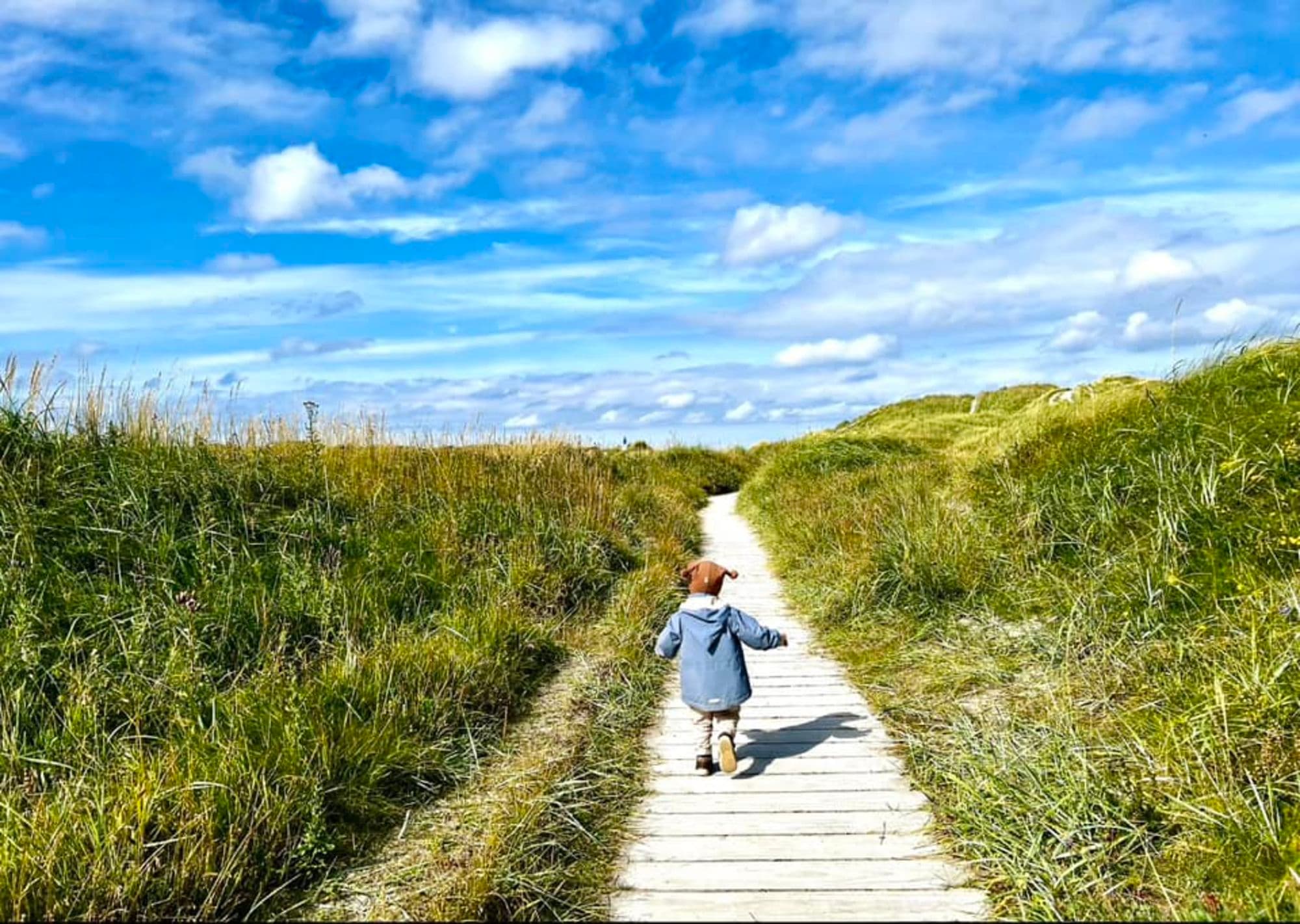 A toddler on walkpath towards the beach